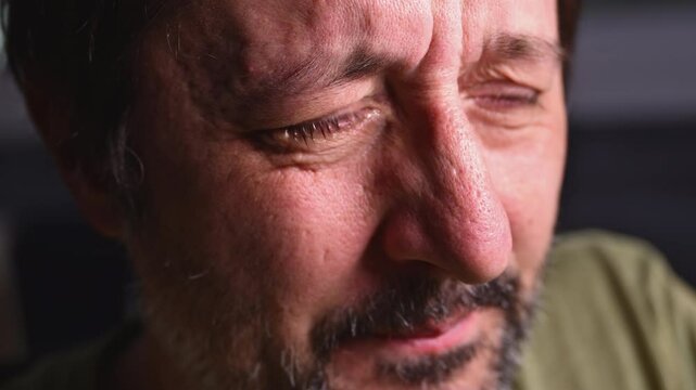 Man crying in dark room, sadness and grief concept, low key with selective focus
