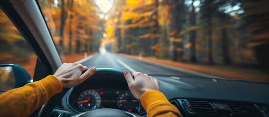 A scenic drive through a vibrant autumn forest with hands gripping the steering wheel, capturing the beauty of the season.