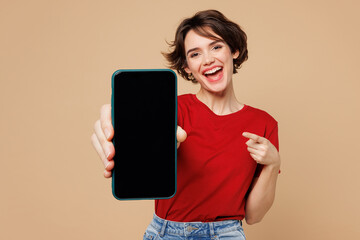 Young happy woman she wear red t-shirt casual clothes hold in hand use point finger on mobile cell...