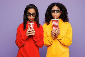 Two young little kid teen girls women they wear red yellow hoodie casual clothes hold in hand cup of soda pop drink cola fizzy water isolated on plain pastel light purple background Lifestyle concept