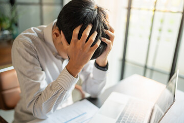 Asian Business man tiredness and stress while having headache. Painful men are stressed at work in office