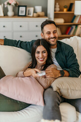 Shot of a beautiful mid adult happy couple sitting on a couch at home and watching tv