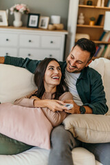 The couple Watches TV together while Sitting on a Couch in the Living Room and Bonding