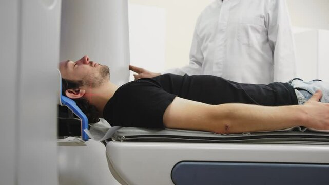 In a modern diagnostic center, a young male patient undergoes an MRI or CT scan with professionals by his side. This scene captures the blend of cutting-edge technology and expert care in healthcare.