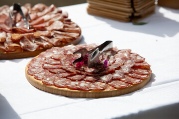 Sliced sausage arrangement on wooden platter at buffet table