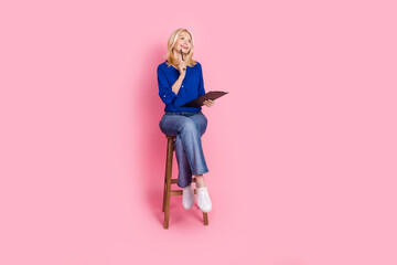 Full body photo of attractive retired woman sit chair write paperholder dressed stylish blue clothes isolated on pink color background