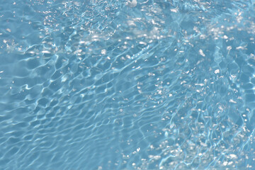 Blue water with ripples on the surface. Defocus blurred transparent blue colored clear calm water surface texture with splashes and bubbles. Water waves with shining pattern texture background.