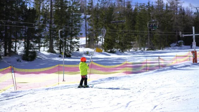 Little boy lifting on the ski drag lift rope, slow motion 