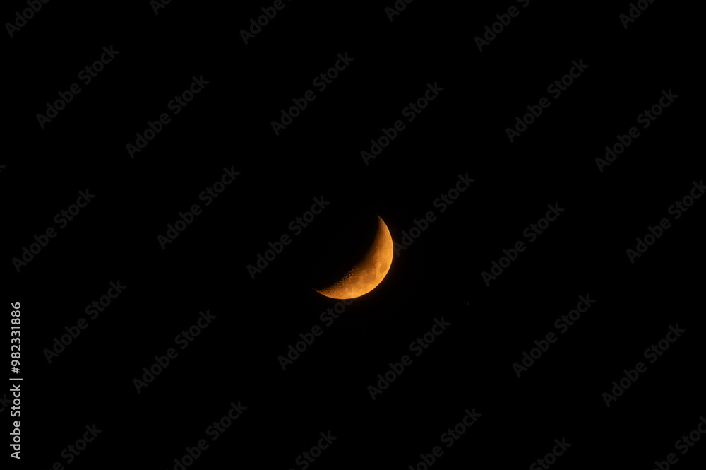 Wall mural a high-resolution image of an yellow crescent moon against a dark sky. the moon is crisp and detaile