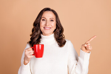 Photo of pretty cute woman wear trendy clothes hold tasty coffee recommend empty space isolated on beige color background