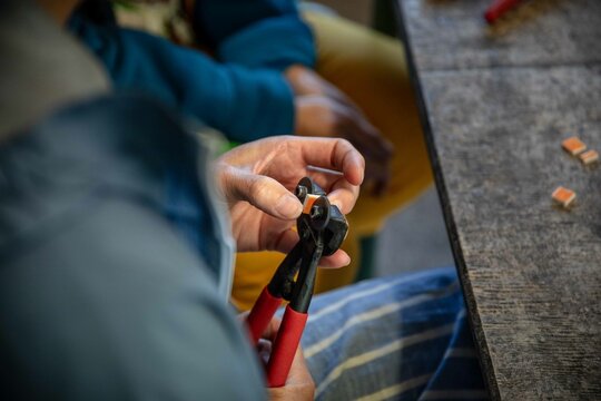 Photographie d'une personne en train de couper un morceau de carrelage avec une pince pour faire de la mosa&iuml;que
