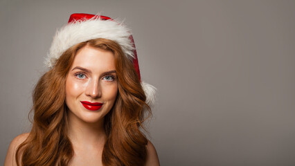 Pretty Christmas woman in Santa hat with make-up and cute positive smile looking at camera, fashion portrait