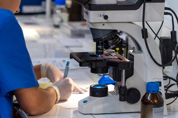 Scientist woman on university lab working with microscope and writing notes
