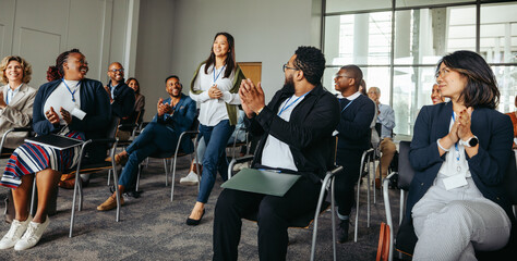 Professional speaker entering stage at business conference with audience clapping