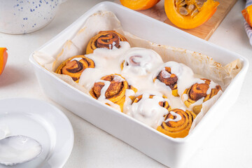 Homemade sweet autumn pumpkin cinnamon swirled bun rolls, pumpkin cinnabons with pecan nuts, cinnamon and creamy cheese icing