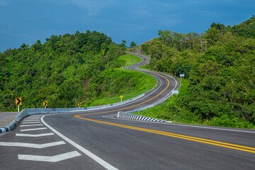 Long curvy forest asphalt road over the hills. Beautiful curved road in the forest. Side view of road