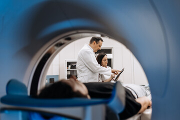 Fototapeta premium A patient undergoes an MRI or CT scan as doctors review images in a modern diagnostic center. This scene highlights the synergy between advanced technology and healthcare for accurate diagnoses.