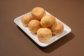 stack of Cheese bread on the plate, Brazilian pao de queijo mineiro, brown background