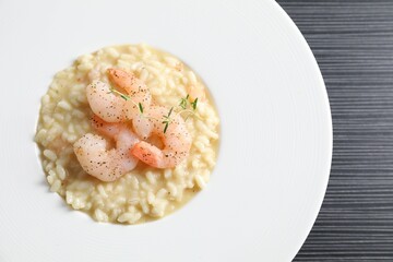 Delicious risotto with shrimps and cheese on black table, top view