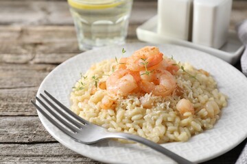 Delicious risotto with shrimps and cheese on wooden table, closeup