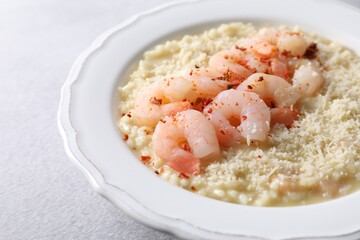 Delicious risotto with shrimps and cheese on light grey table, closeup