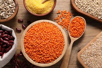 Different types of cereals, seeds and legumes on wooden table, flat lay