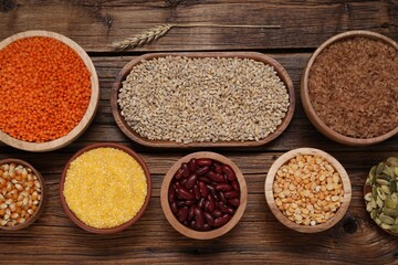 Different types of cereals, seeds and legumes on wooden table, flat lay
