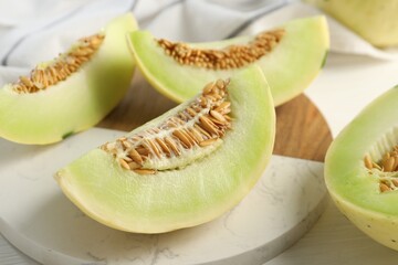 Fresh cut honeydew melon on white wooden table, closeup