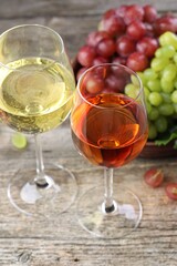 Fresh ripe grapes and glasses of wine on wooden table, closeup
