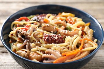 Stir-fry noodles with sea food and vegetables on wooden table, closeup