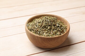 Dried oregano in bowl on wooden table, closeup