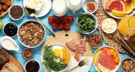 Different tasty food served for brunch on light blue wooden table, flat lay