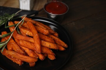 Sweet potato fries, rosemary and ketchup on wooden table, closeup