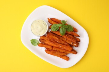 Sweet potato fries, basil and sauce on yellow background, top view