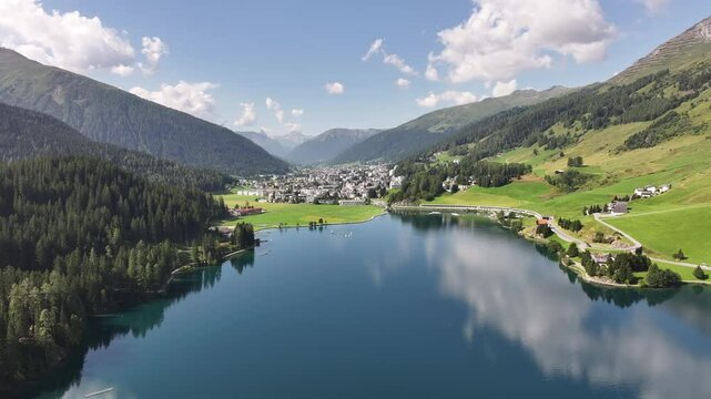 Drone view of Davos, a town in the Graub&uuml;nden canton of Switzerland, with a calm, reflective lake surrounded by serene nature.