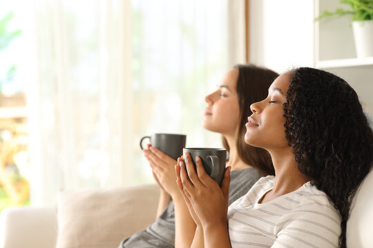 Interracial roommates relaxing drinking coffee at home
