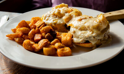grilled homemade biscuit topped with two sausage patties, two scrambled eggs bacon cheddar cheese and sausage gravy served with home fries