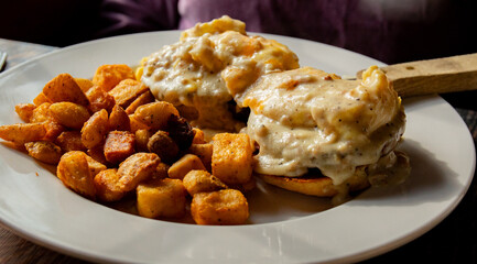 grilled homemade biscuit topped with two sausage patties, two scrambled eggs bacon cheddar cheese and sausage gravy served with home fries