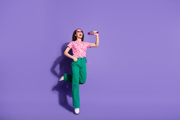 Full body photo of attractive young woman sing karaoke microphone dressed stylish pink clothes isolated on violet color background