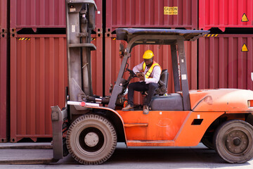 Worker is working in container yard. Worker drive or control the forklift.