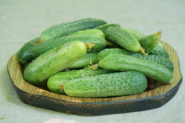 Young cucumbers on a wooden plate