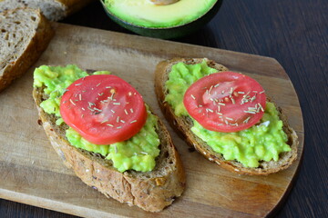 two slices of bread with avocado on it and a tomato on the top