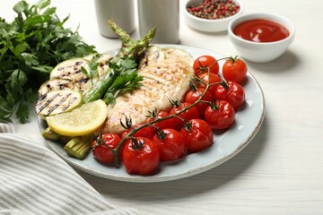 Delicious grilled vegetables and chicken breast served on white wooden table, closeup