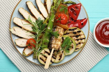 Delicious grilled vegetables and cut chicken meat served with sauce on light blue wooden table, flat lay