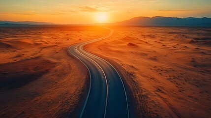 Fototapeta premium An aerial view showcases a winding desert highway through golden sand dunes, emphasizing dramatic shadows and warm sunset tones in a cinematic landscape with vast expanses of the Sahara.