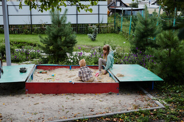 Little boy and girl playing in the sandbox on the playground. Happy childhood, having fun on...