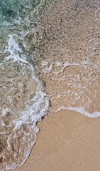 A detailed view of a sandy beach and a breaking wave