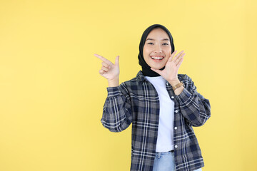 Happy Indonesian Young Woman in Black Veil or Hijab, Pointing at Copy Space with Right Hand