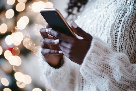 African American black girl holding in hands mobile phone. She orders gifts online, congratulates on the holiday. Christmas concept.