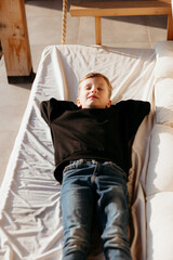 Boy relaxing with eyes closed lying on swinging bed in log cabin